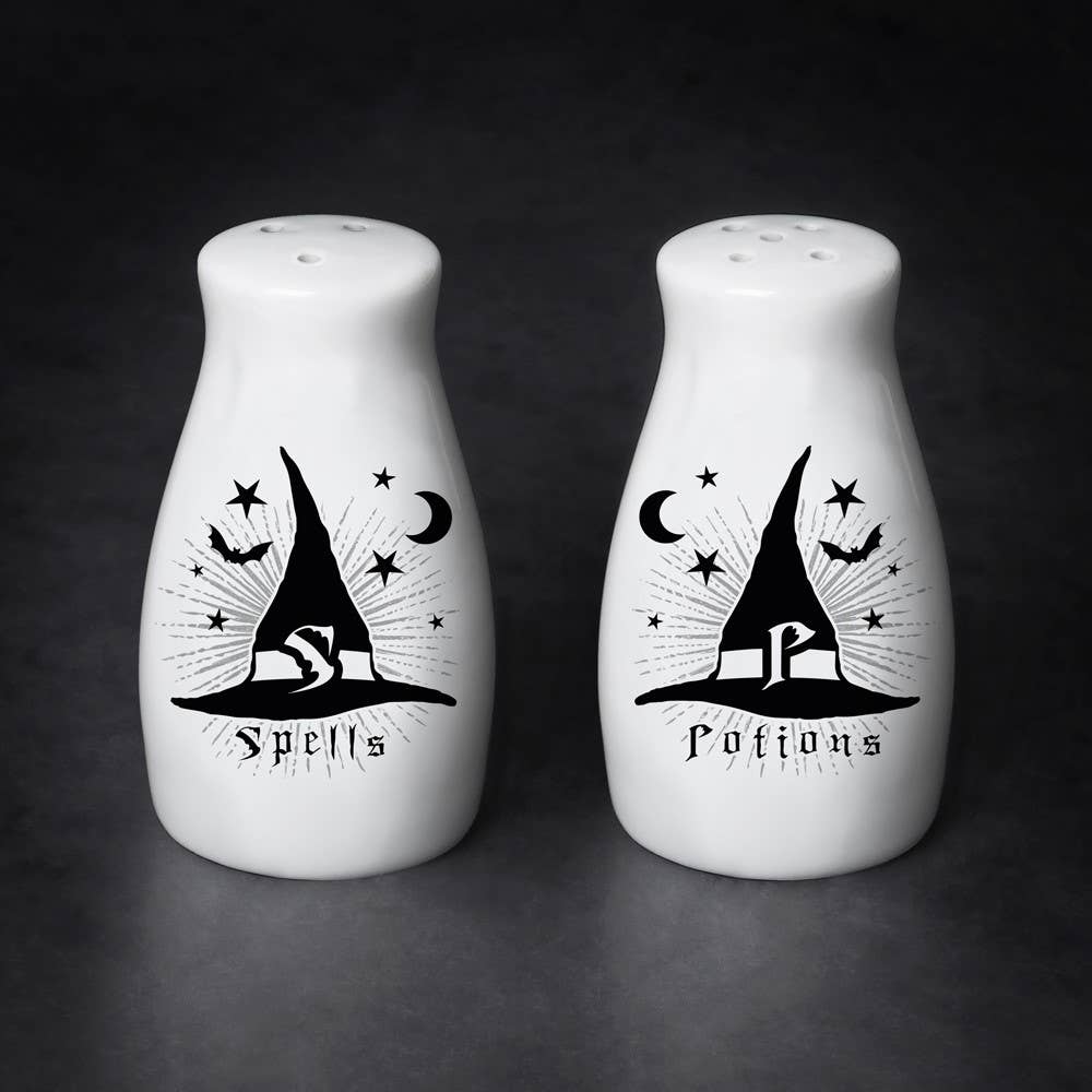 Two white salt and pepper shakers with black witch hat designs on a dark background