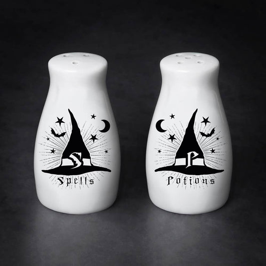 Two white salt and pepper shakers with black witch hat designs on a dark background