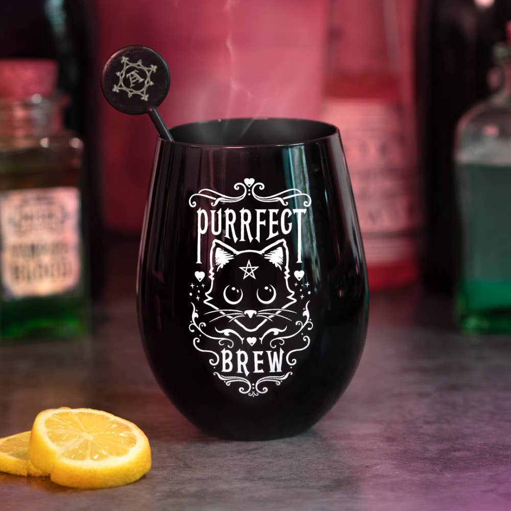 Black wine glass with 'Purrfect Brew' design on a bar counter with lemon slices and bottles in the background.