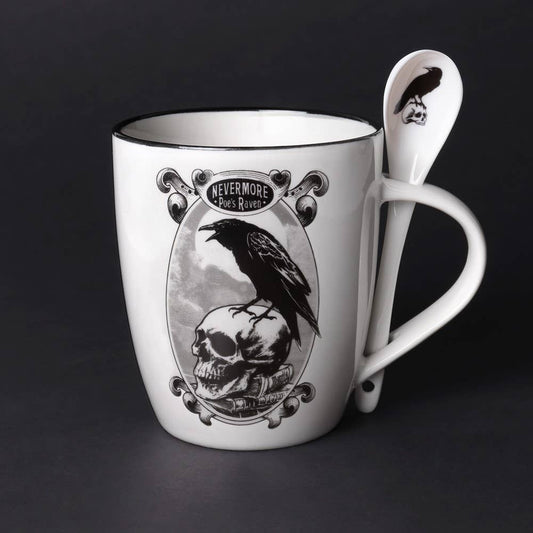 White mug with skull and raven design, accompanied by a matching spoon on a dark background