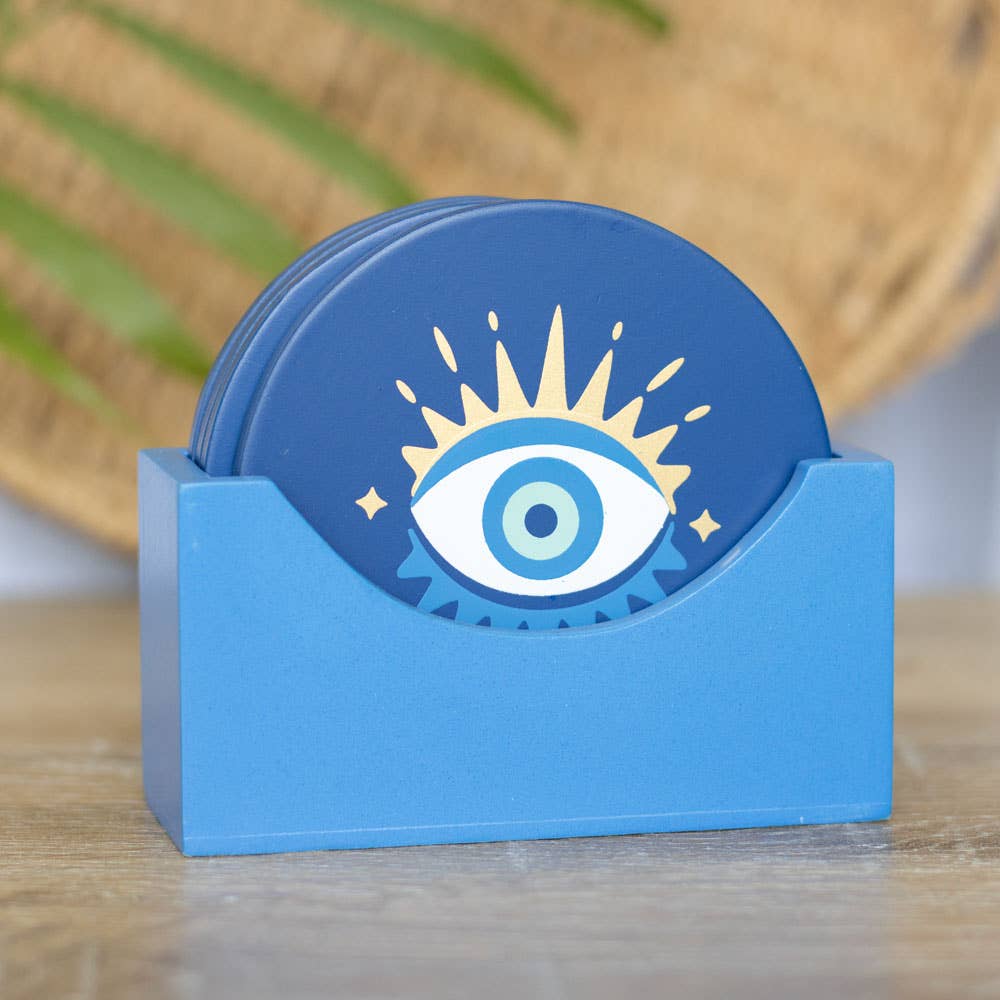 Blue coaster set with eye design in a holder on a wooden surface