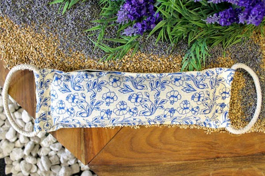 Decorative pillow with blue floral pattern on a wooden surface with lavender and greenery.