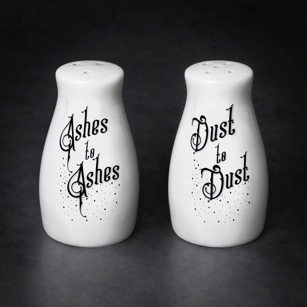 Two white salt and pepper shakers with black text on a dark background