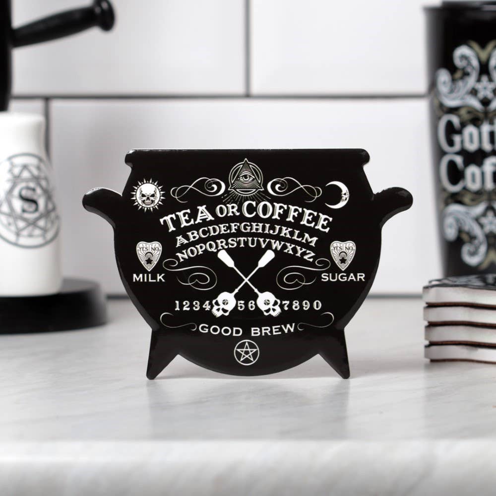 Black cauldron-shaped coaster with tea and coffee text on a kitchen counter.