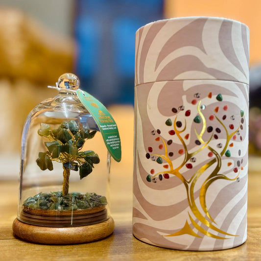 Decorative item with a tree inside a glass dome and a cylindrical container with tree design on a wooden surface.