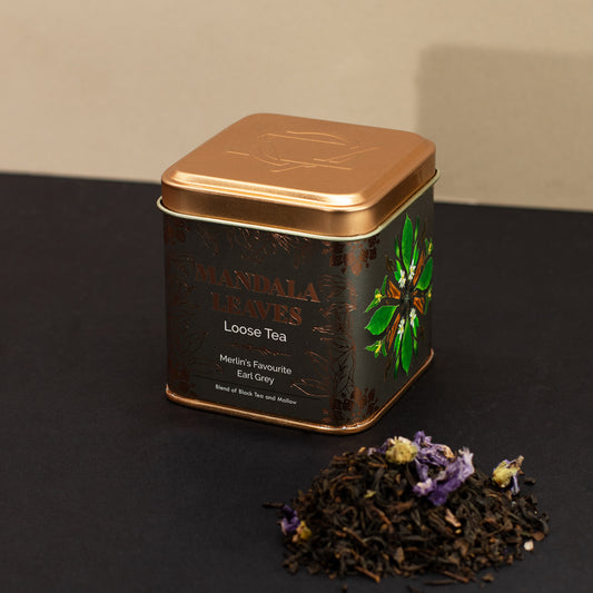 Mandala Leaves Merlin's favourite earl grey loose tea next to a black and gold tin
