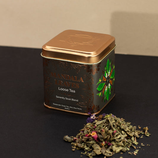 Mandala leaves serenity souk blend loose tea next to a black and gold tin