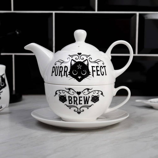 White teapot and cup set with black cat design and text on a kitchen counter.