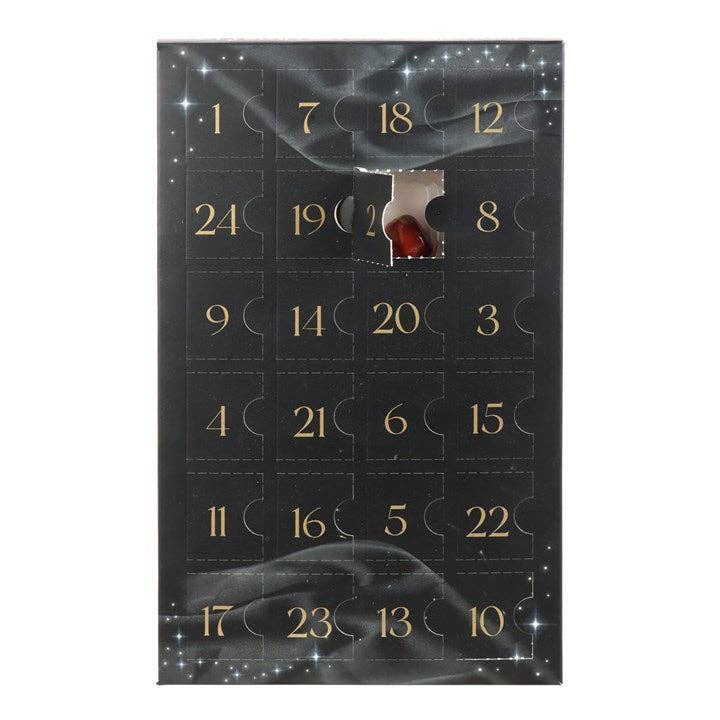 Black advent calendar with gold numbers and a red stone peeking out.