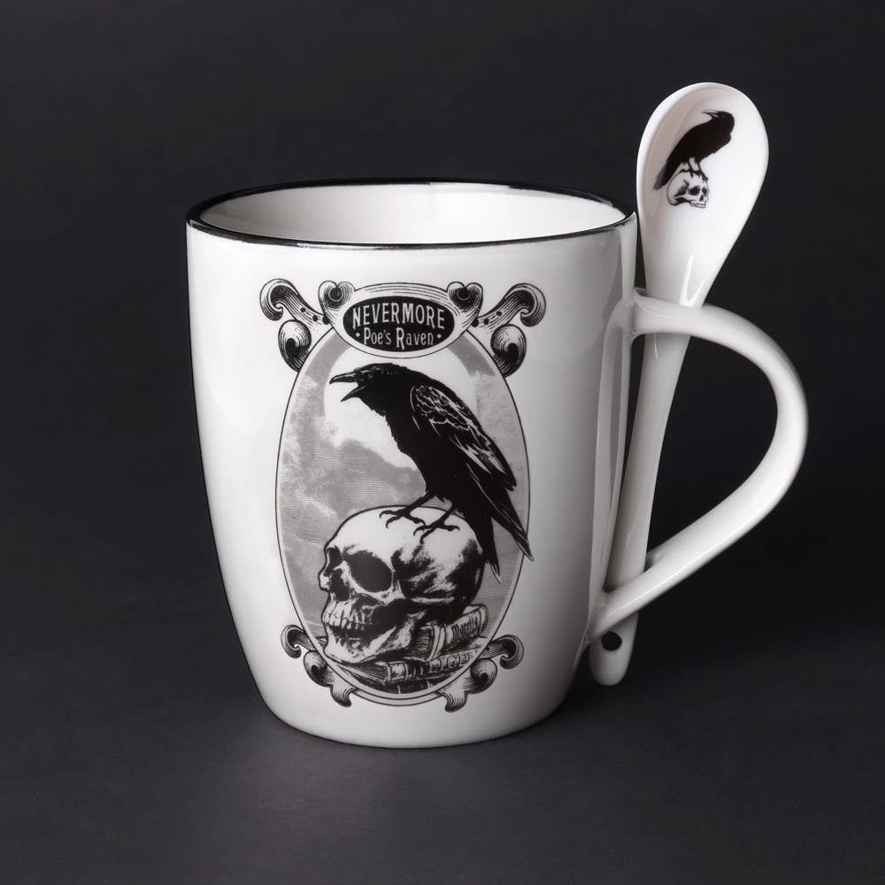 White mug with skull and raven design, accompanied by a matching spoon on a dark background