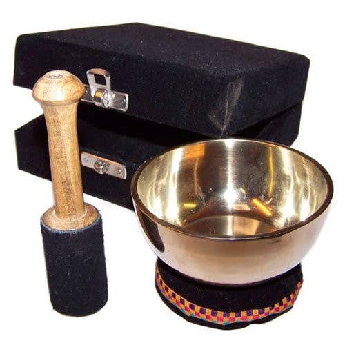 Brass singing bowl with wooden mallet and black carrying case on a white background