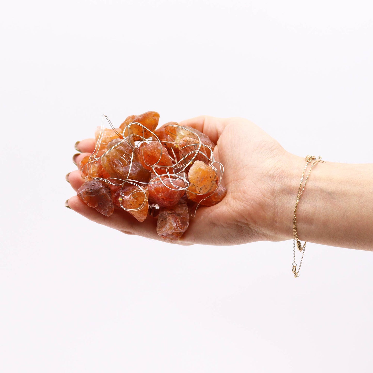 Orange jade gemstone lights being held in palm of hand
